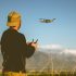 young-man-flying-a-drone-at-dusk-with-mountains-in-the-background-picture-id956250158